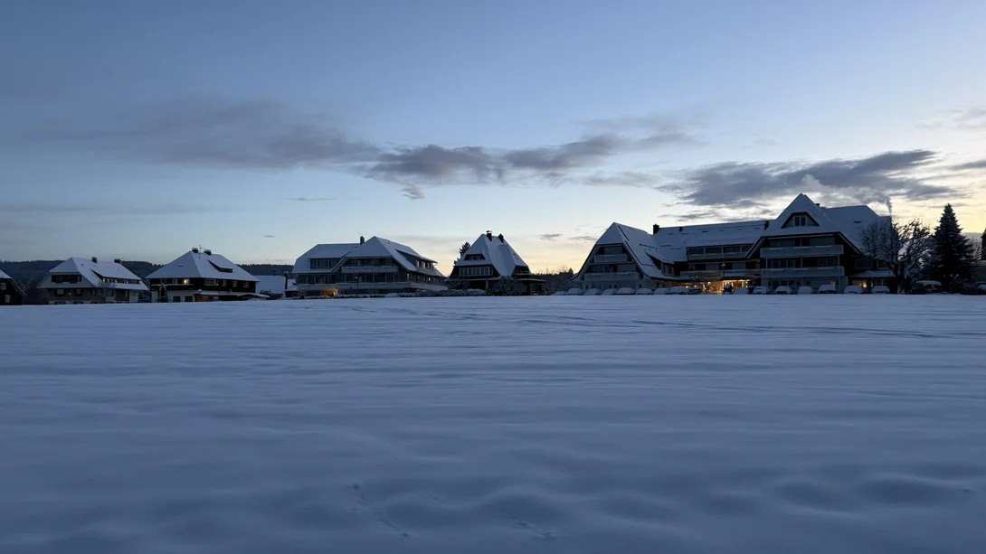 Reppert, Ihr Hotel in Hinterzarten im Schwarzwald Verschneite Hotelgebäude in der Dämmerung, umgeben von einer weiten Schneefläche