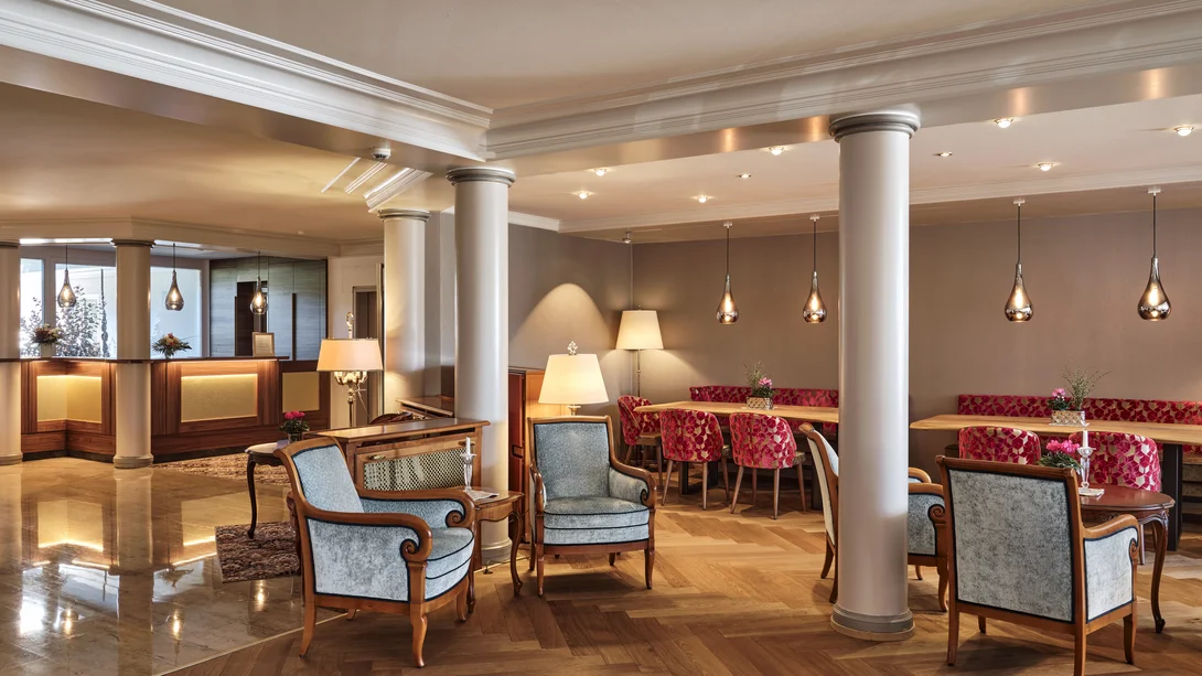 Reppert, Ihr Hotel in Hinterzarten im Schwarzwald Heller Hotel-Lobbybereich mit Säulen, Sesseln und roten gepolsterten Stühlen