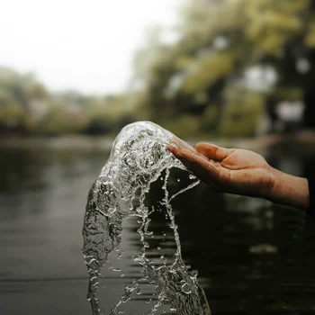 Reppert, Ihr Hotel in Hinterzarten im Schwarzwald Hand fängt spritzendes Wasser über dem Fluss mit verschwommenem Hintergrund