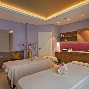 Your spa hotel in the Black Forest | Hotel Reppert Massage room with two tables, warm lighting, and floral decorations