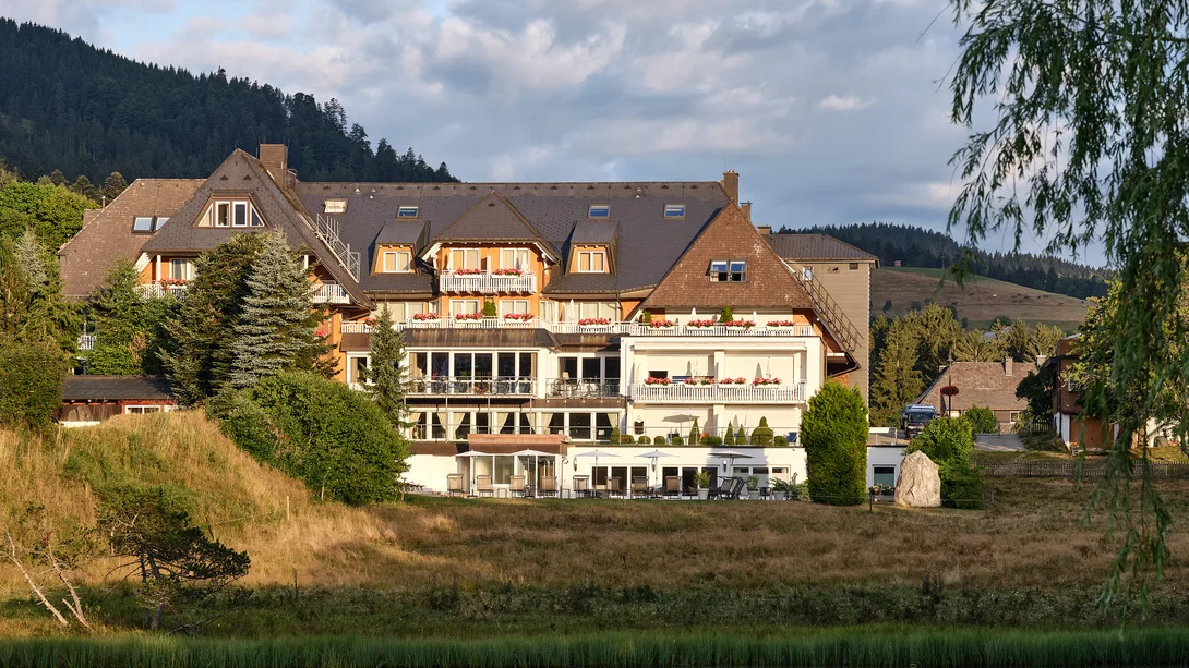 Reppert, Ihr Hotel in Hinterzarten im Schwarzwald Hotelgebäude am See mit Spiegelung und Bergkulisse